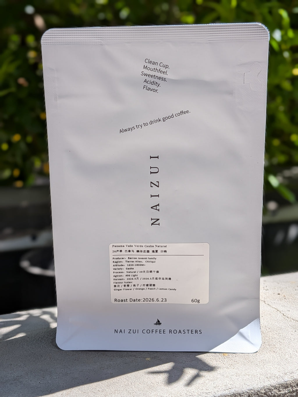 A 60g bag of NAIZUI coffee in a white stand-up pouch, photographed outdoors on a stone surface with blurred green foliage in the background.