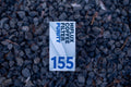 A rectangular HIFLUX Coffee Filter Purify replacement filter card, printed with blue text and the number 155, placed on a bed of dark gray gravel.